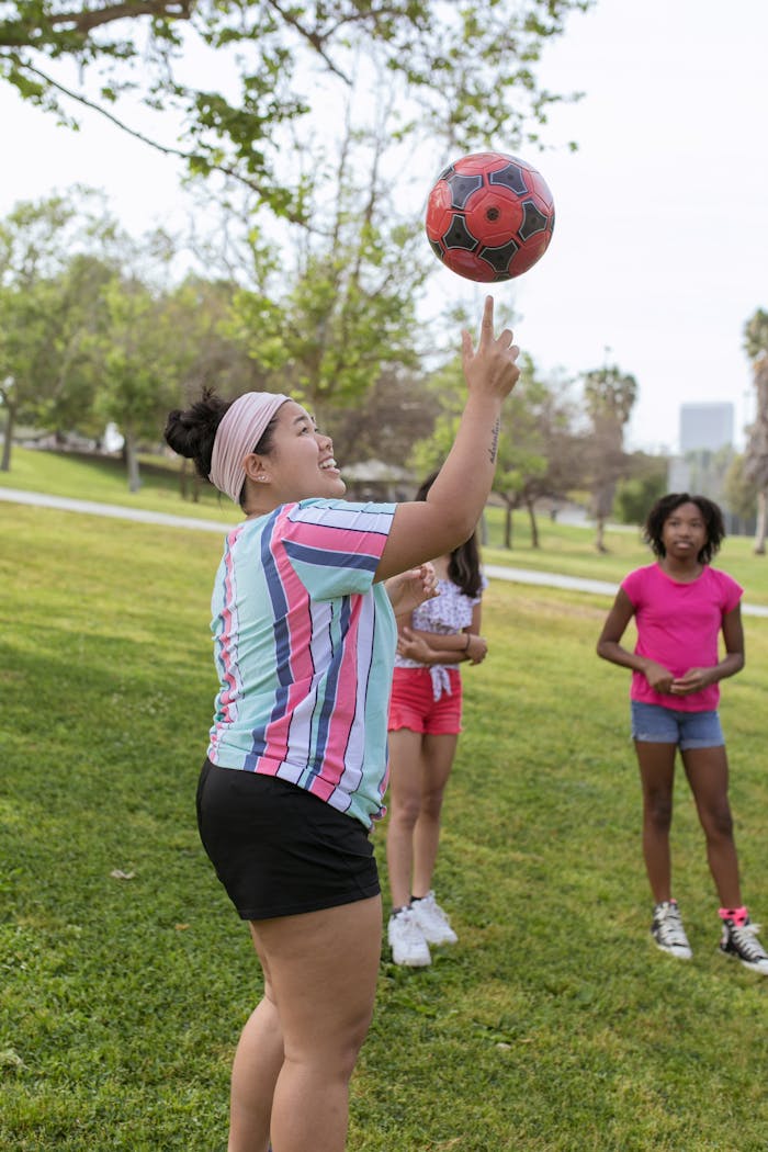 Young girls enjoying a sunny day playing ball in the park, capturing joy and friendship.